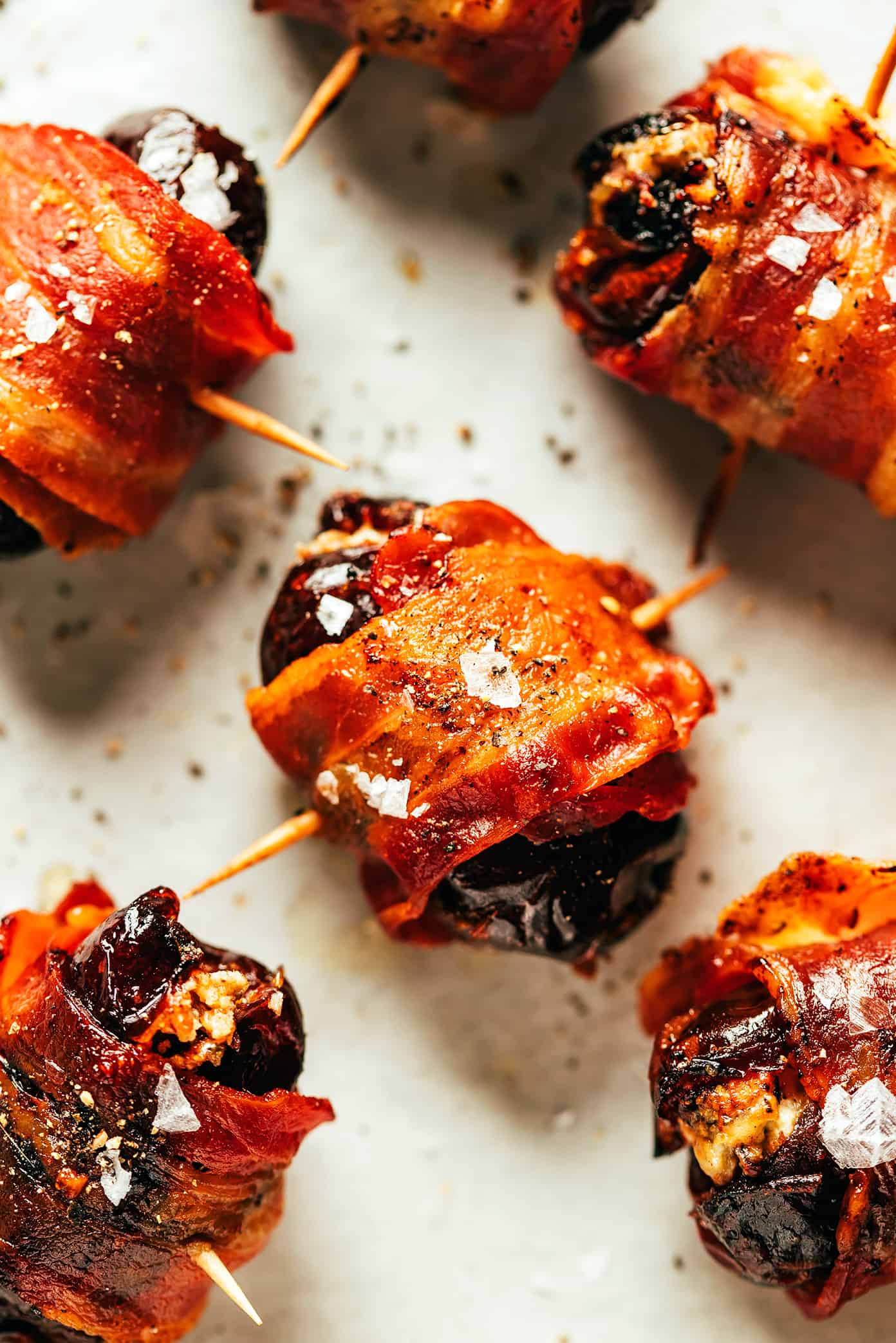 My favorite bacon-wrapped dates recipe is made with crispy bacon, tender Medjool dates, and stuffed with your choice of cheese (blue, feta, goat, cheddar, etc). A delicious appetizer that's easy to make and always a party favorite! | gimmesomeoven.com Bacon-Wrapped Dates Closeup