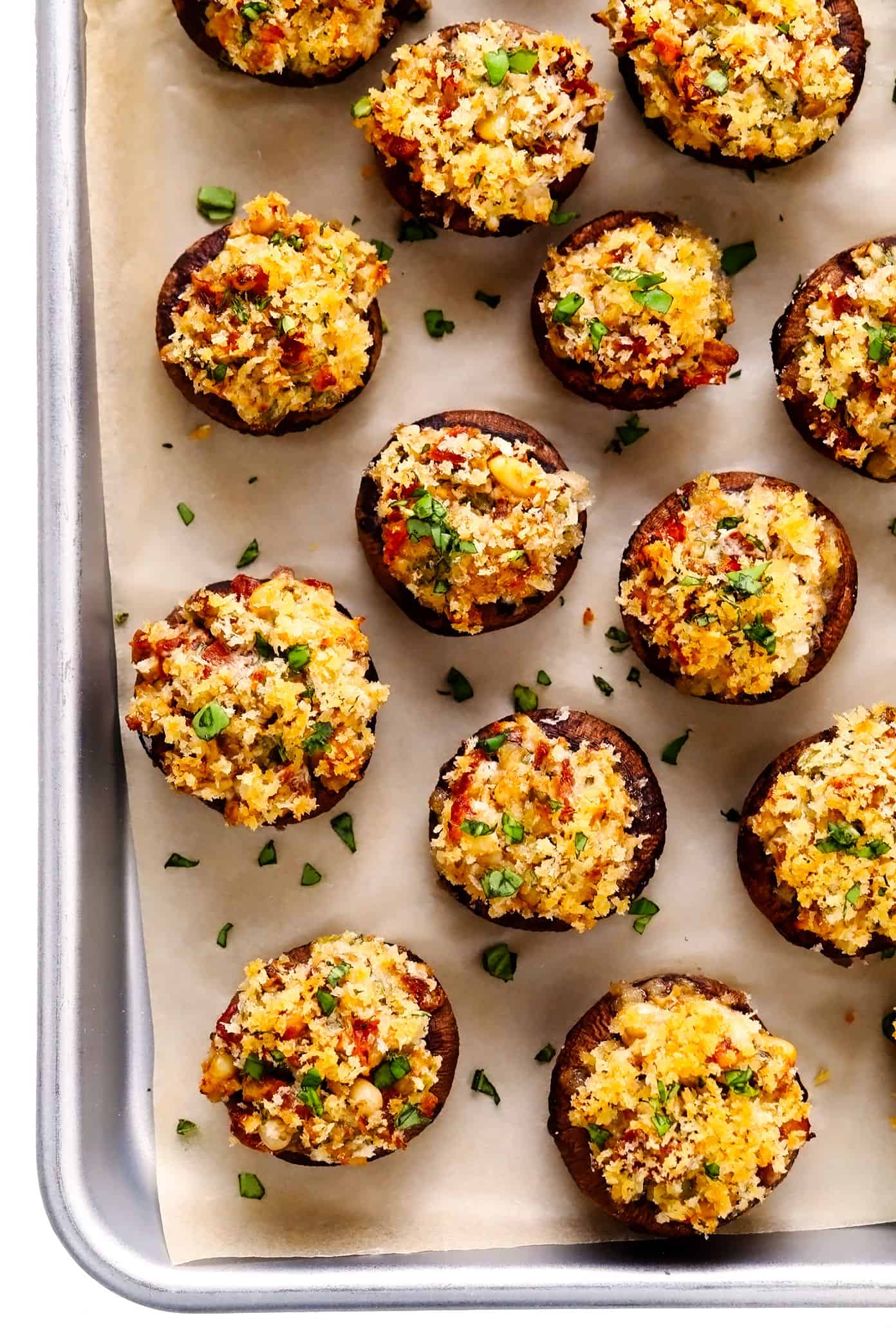 This easy stuffed mushrooms recipe is made with a garlicky goat cheese, sun-dried tomato, pine nut and basil filling and topped with crispy toasted breadcrumbs. The perfect vegetarian appetizer that's easy to make ahead of time (up to 1 day in advance) and always a crowd fave! | gimmesomeoven.com Vegetarian Stuffed Mushrooms on Baking Sheet