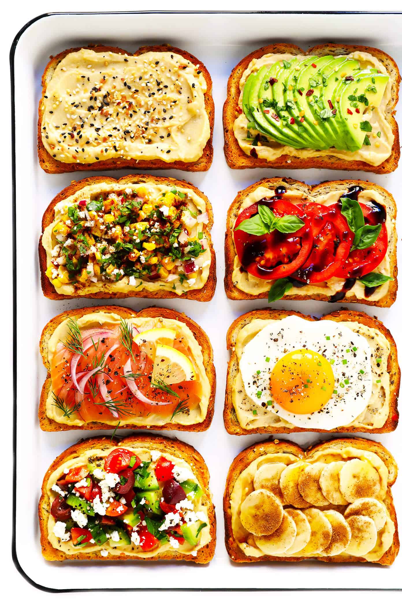 Hummus Toast is fun to customize with your favorite toppings, and makes for a delicious easy breakfast, lunch, dinner or healthy snack! Read more for details on 8 of our favorite toppings -- "everything", avocado, elote, tomato basil, lox, fried egg, mediterranean or honey banana. | gimmesomeoven.com #hummus #toast #healthy #breakfast #dinner #lunch #snack Hummus Toast