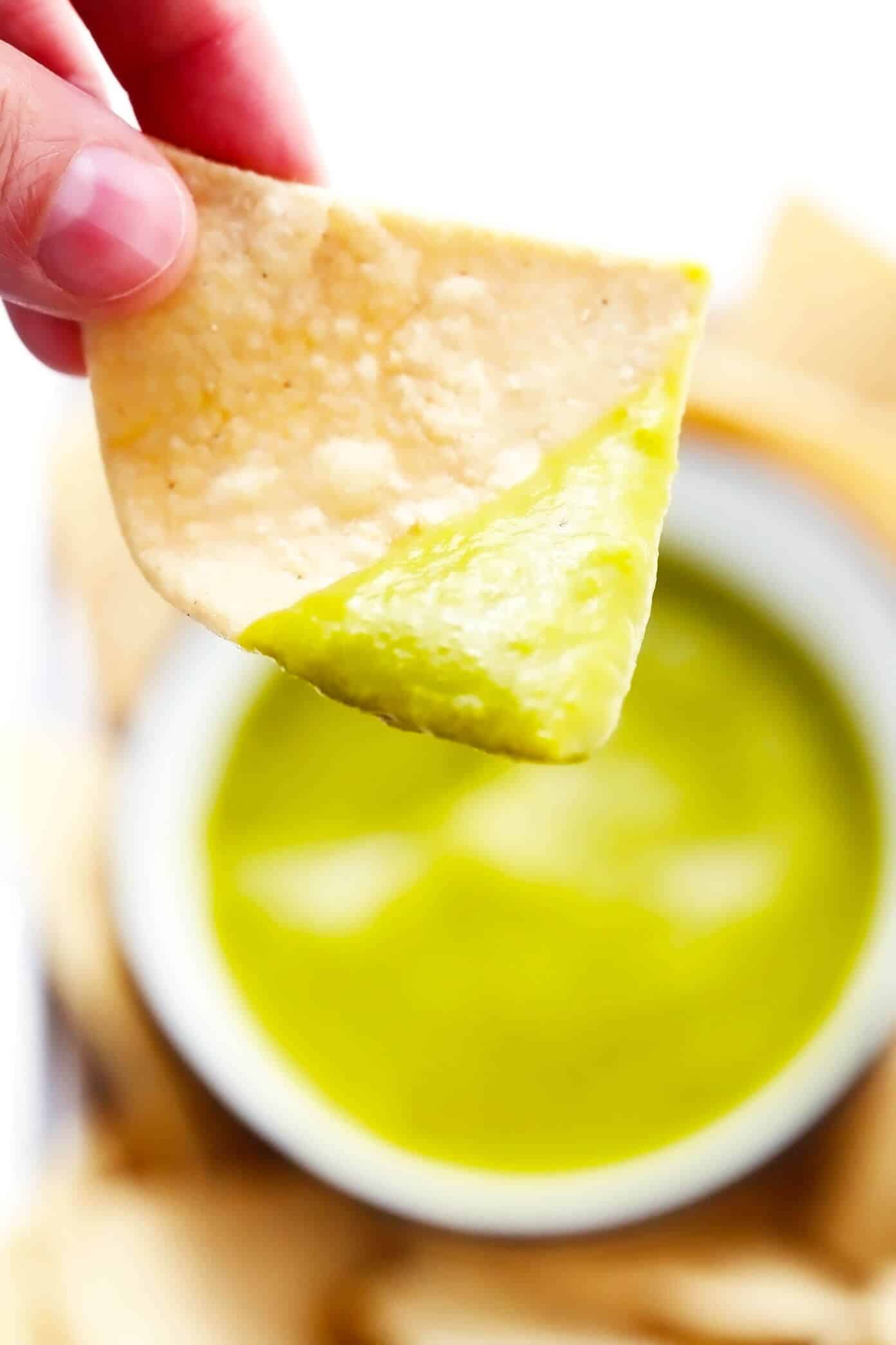This 5-ingredient creamy jalapeño salsa recipe is easy to make in 30 minutes and irresistibly garlicky and flavorful. Perfect for dipping with chips or drizzling on whatever other Mexican-inspired dishes you love best. It is naturally gluten-free and vegan, and options are included to make this salsa as mild or spicy as you prefer. | gimmesomeoven.com Scooping a tortilla chip in jalapeño salsa