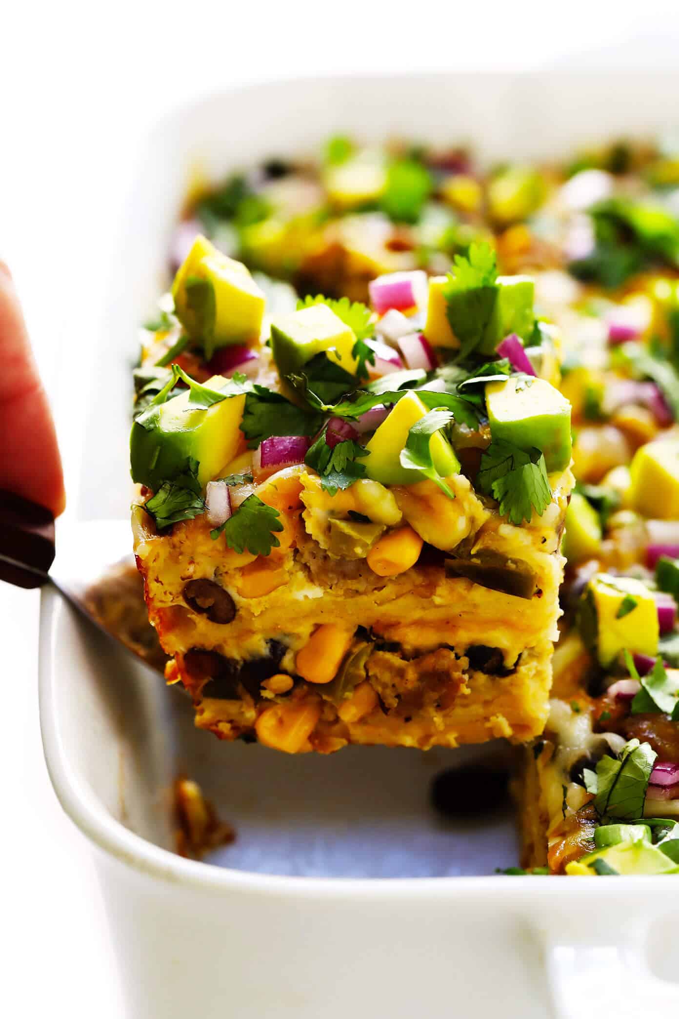 This amazing Mexican breakfast casserole recipe is loaded up sausage (or chorizo), eggs, cheese, veggies, tortillas, avocado, and your choice of red or green salsa. It's a gluten-free make-ahead breakfast casserole recipe that's easy to make...and always a fave! | gimmesomeoven.com #breakfast #casserole #mexican #glutenfree #brunch #avocado #enchilada #healthy Amazing Mexican Breakfast Casserole