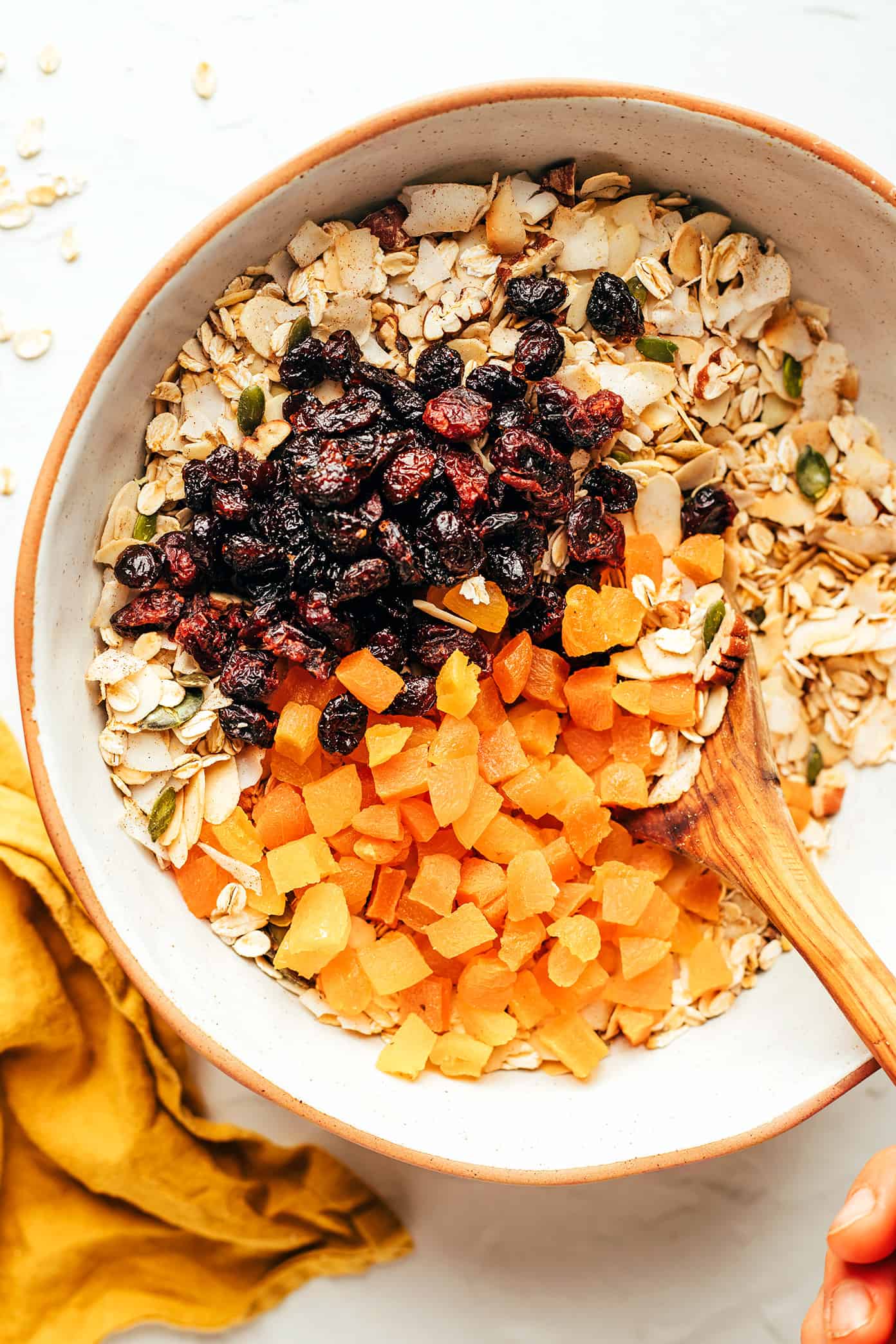 This delicious homemade muesli recipe is easy to make and customize with your favorite blend of oats, nuts, seeds, dried fruit, coconut (optional) and spices. Serve with hot or cold milk, prep "overnight oats"-style, layer as a parfait with Greek yogurt, or however you love best. Always such a great healthy and easy breakfast! | gimmesomeoven.com Muesli ingredients in mixing bowl